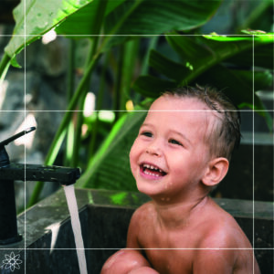 young child sitting in an outdoor bath, smiling